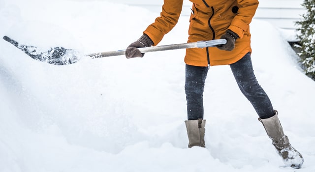 Person shoveling snow practicing safe snow shoveling tips.