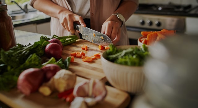 person cutting vegetables in a kitchen