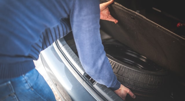 man getting spare tire from car trunk