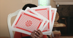 boy holding up oversized playing cards