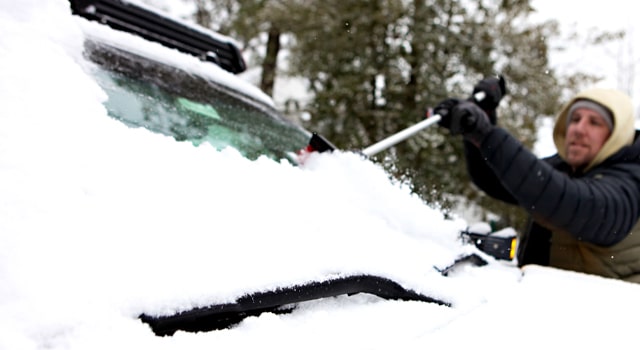 Person with scraper learning how to get ice off windshield