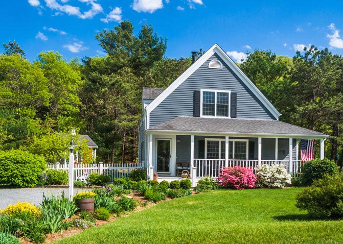 Grey sided home with trees and bushes