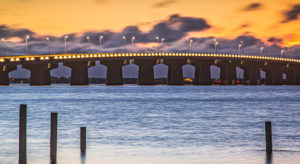 bridge over water with clouds at sunset