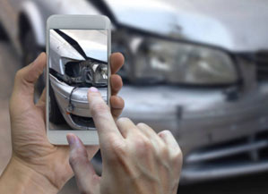 hands taking photo of damaged car with phone