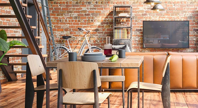 Wooden chairs around a square wooden table near brick wall