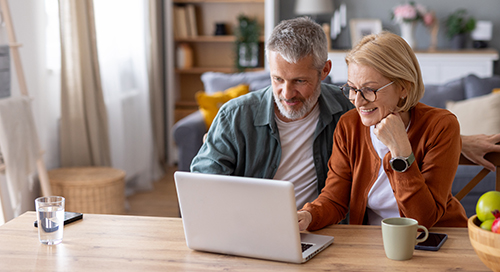 Man and woman smiling in front of a laptop