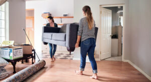 Two women moving a sofa in a room