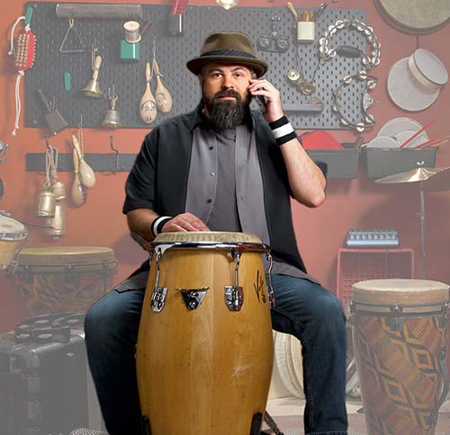 Man playing large bongo drum answering his cell phone