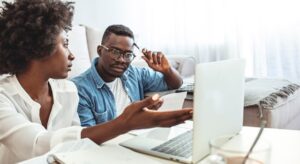 Young couple calculating best way to lower car insurance deductible.