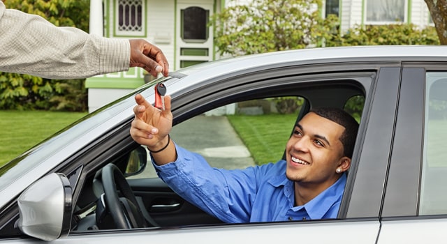 Person handing keys to someone else to drive a car that’s covered by insurance.