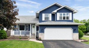 Blue dwelling with attached garage and front porch