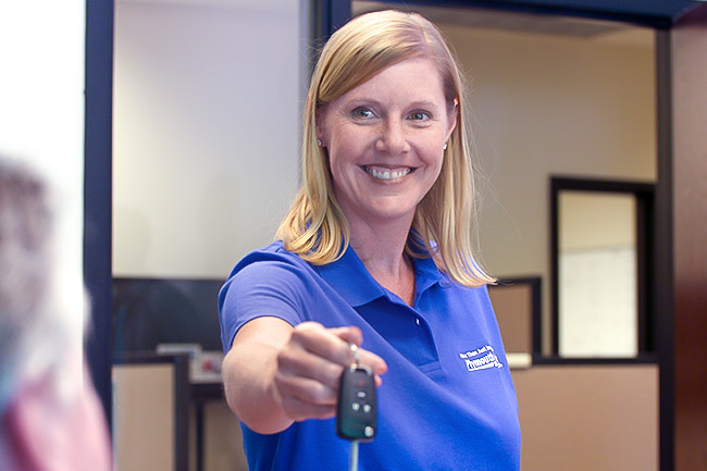 woman in blue shirt handing car keys over to customer