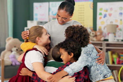 Female teacher hugging her students in a classroom