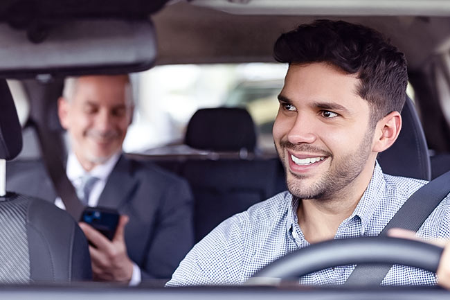 Uber driver smiling at passanger in back seat of car