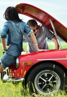 young couple sitting on car with hood up
