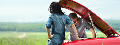 young couple sitting on car with hood up