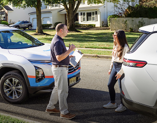 Plymouth Rock appraiser talking to woman next to her car