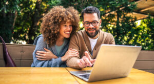 A couple using a laptop outside.